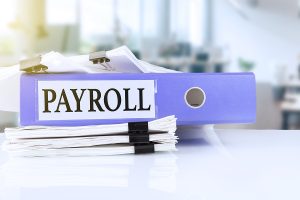 Payroll folder and tax documents on a desk in a modern office setting