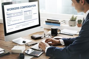Man working on workers’ compensation form at office desk with computer