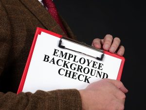 Person holding a clipboard labeled Employee Background Check