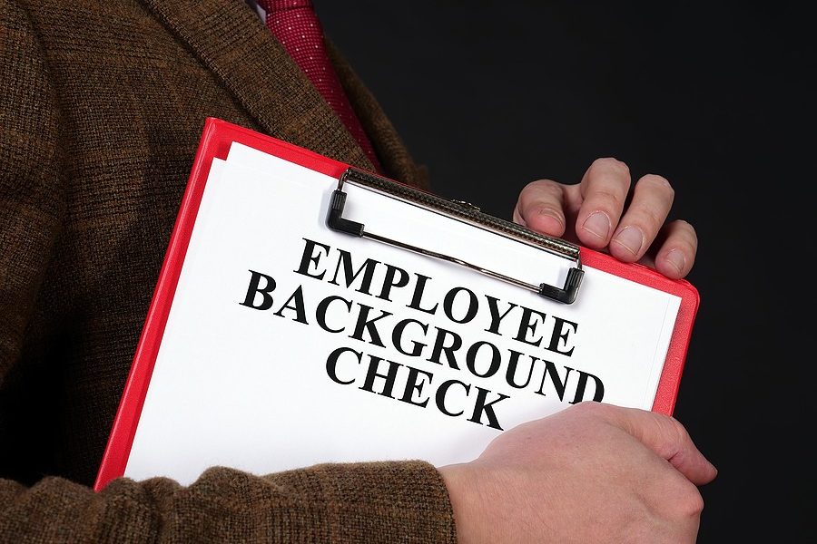 Person holding a clipboard labeled Employee Background Check