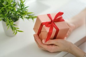 Hands holding a wrapped holiday gift with a red ribbon