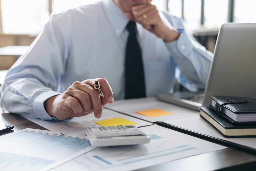 Business owner calculating effective tax rate with calculator and financial documents