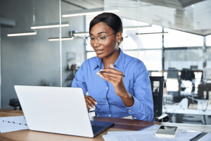 HR professional reviewing payroll and compliance documents on laptop